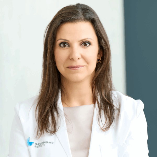 Picture of woman wearing white lab coat and brown hair that goes just past her shoulders, Dr. Denise Al Alam